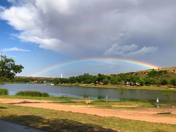 Scenic view of rainbow over lake against sky