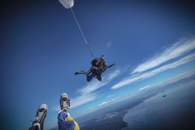 Low angle view of people paragliding against sky