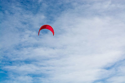 Low angle view of red paragliding against sky