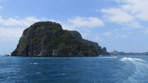 Rock formation in sea against cloudy sky