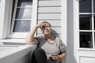 Relaxed senior woman sitting on porch in sunshine