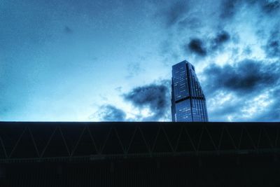 Low angle view of skyscrapers against cloudy sky