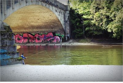 Man under bridge over river