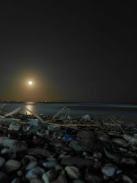 Garbage on rocks at beach against clear sky at night