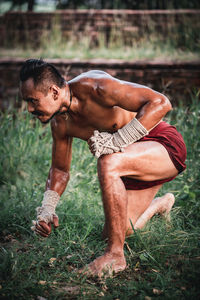 Full length of shirtless man lying on field