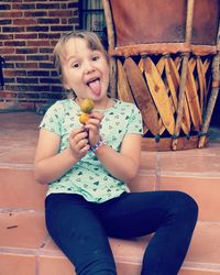 Portrait of girl holding ice cream while sitting on steps