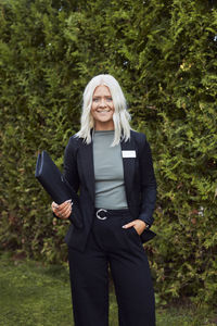 Smiling estate agent standing in front of house