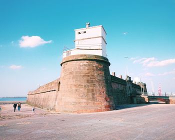 People at observation point by sea against sky