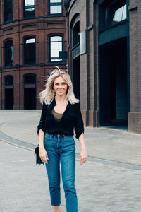 Portrait of teenage girl standing against building