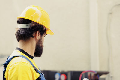 Side view of man wearing helmet against wall