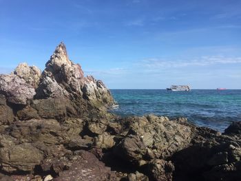Scenic view of rocks in sea against blue sky