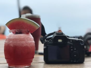Close-up of camera with drink on table