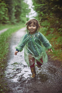 Charming child in a raincoat in the evening forest in denmark