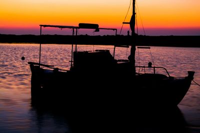 Silhouette boat in sea against sky during sunset