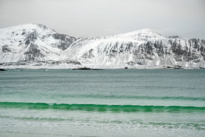 Scenic view of sea by mountain against sky