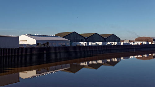 Reflection of buildings in water against clear blue sky