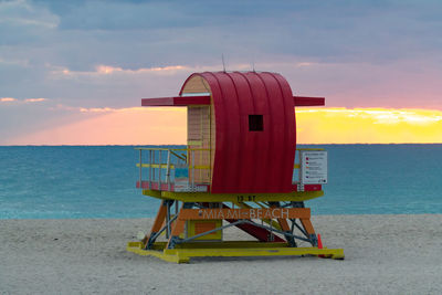 Lifeguard hut on beach against sky during sunset