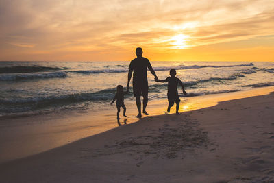 People on beach against sky during sunset