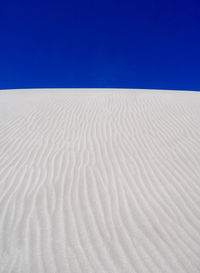 Sand dunes in desert against clear blue sky