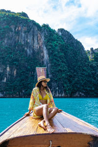 Woman sitting on wooden boat against sky