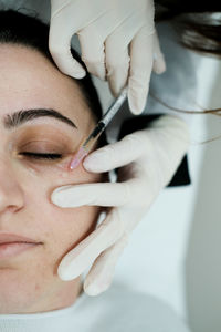 Cosmetologist applying eye mesotherapy to female patient