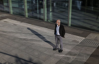 Portrait of adult man in suit against glass wall of a business area