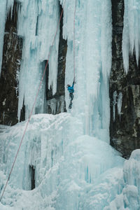 Male ice-climber scaling a massive and treacherous ice wall. 