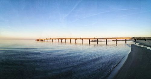 Pier on sea against clear sky during sunset