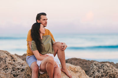 Young woman sitting on rock at beach