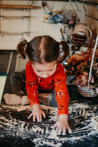 Full length of cute baby girl playing with flour on kitchen counter