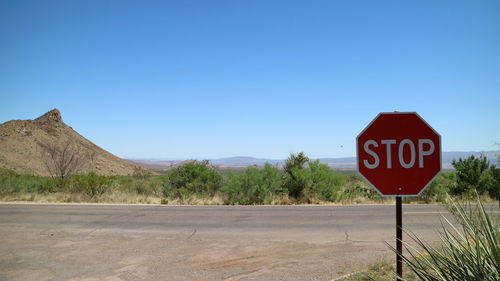 Road sign against clear blue sky