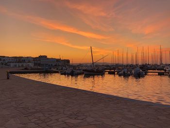 Sailboats moored at harbor during sunset