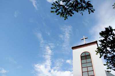 Low angle view of cross and building against sky