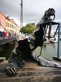 View of statue by canal against sky in city