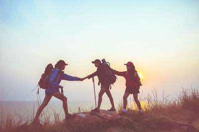 People standing on land against sky during sunset