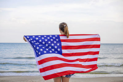 Low angle view of american flag on beach against sky