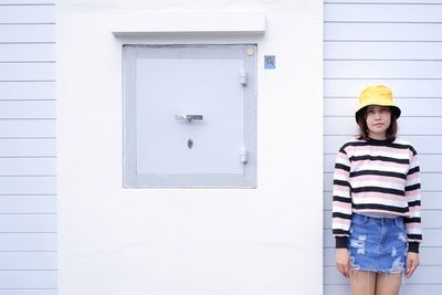 Portrait of smiling woman standing against wall