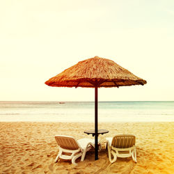 Deck chairs on beach against clear sky