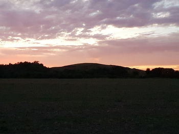 Scenic view of silhouette field against sky during sunset