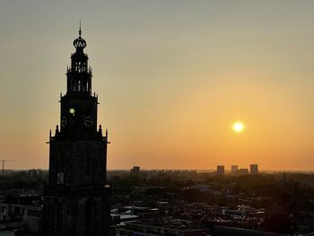 Tower in city against sky during sunset