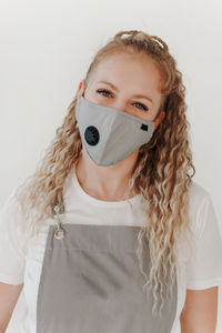 Portrait of young woman wearing mask against white background