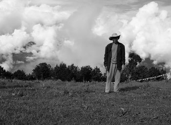 Rear view of man standing on field against sky