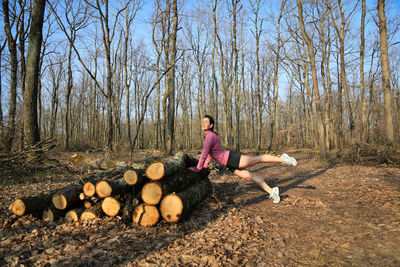 Young woman dancing by logs at forest