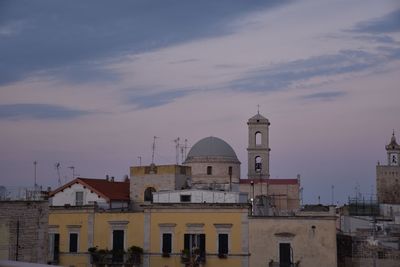 Buildings in city against sky during sunset