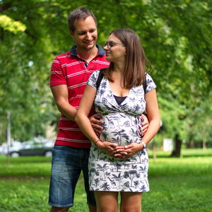 Pregnant couple touching woman's belly standing in park