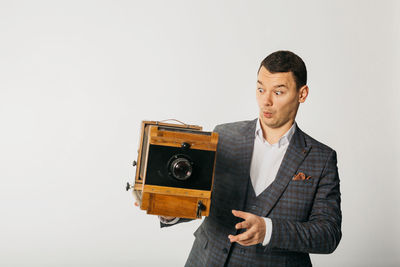 Full length of young man photographing against white background