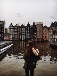 Woman standing by canal in city