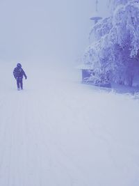 Person on snow covered field against clear sky