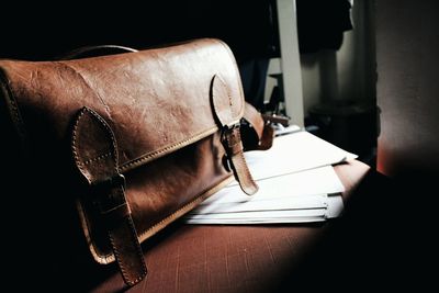 Close-up of leather bag with papers on wooden table