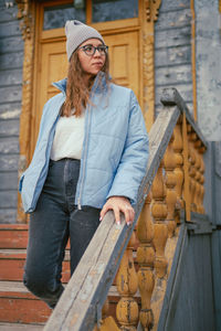 Portrait of smiling young woman standing against wall